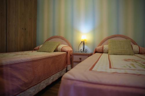 Mediterraneo في فارو دي كوييرا: سريرين في غرفة نوم مع مصباح على طاولة