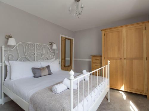 um quarto com uma cama branca e um armário de madeira em Harbourside Cottage em Weymouth