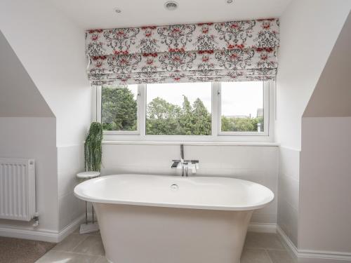 uma banheira branca na casa de banho com uma janela em Cascon em St Asaph