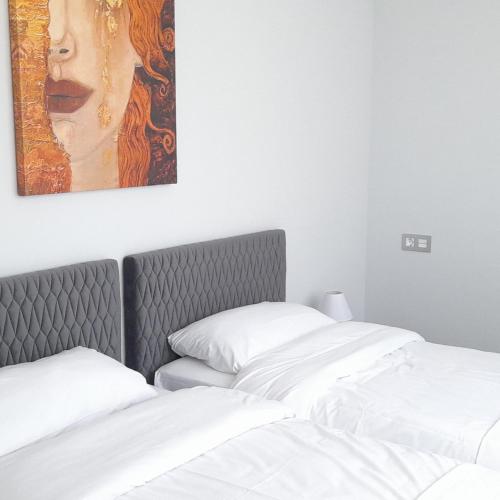 two beds in a room with a painting on the wall at Mar Apartments Alicante, Playa de San Juan in Alicante