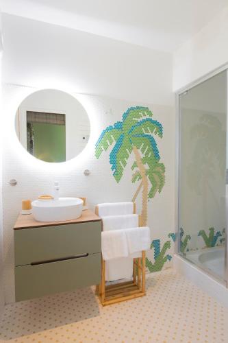 La salle de bains est pourvue d'un lavabo et d'une fresque murale de palmiers. dans l'établissement VILLA BAUHINIA - Golfe de Saint-Tropez, au Plan-de-la-Tour