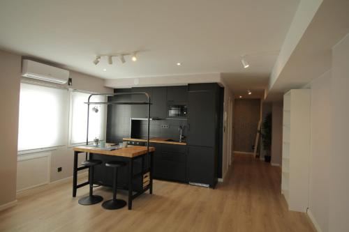 a kitchen with black cabinets and a wooden counter top at Espectacular loft lleno de luz y espacio! in Zaragoza