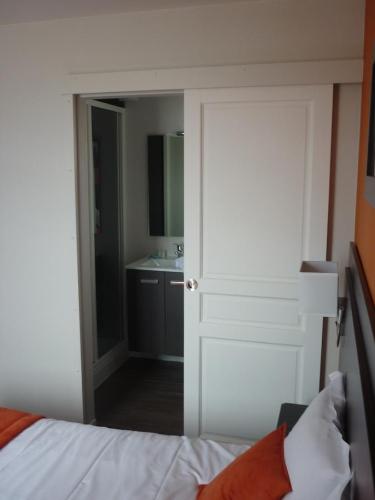 a bedroom with a bed and a bathroom with a sink at Hotel De La Plage in Quiberville
