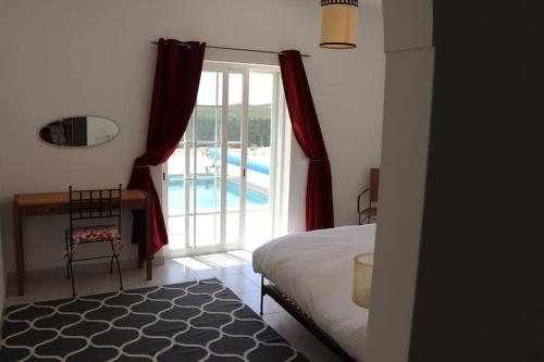 a bedroom with a bed and a window with a pool at Stunning Villa with Pool & View near beach in Budens