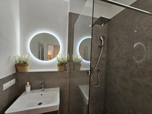 La salle de bains est pourvue d'une douche, d'un lavabo et de deux miroirs. dans l'établissement 2 room Apartment, new building, Bosákova street, 29, à Bratislava