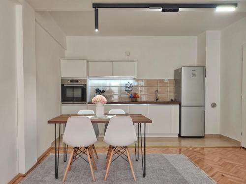 eine Küche mit einem Holztisch und weißen Stühlen in der Unterkunft Businoski's Apartment in Ohrid