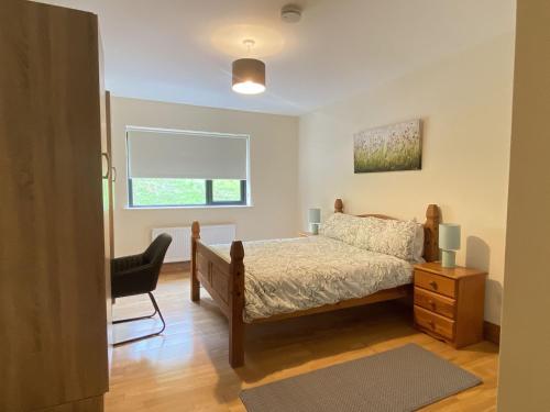 a bedroom with a bed and a chair and a window at Cottage 442 - Oughterard in Oughterard