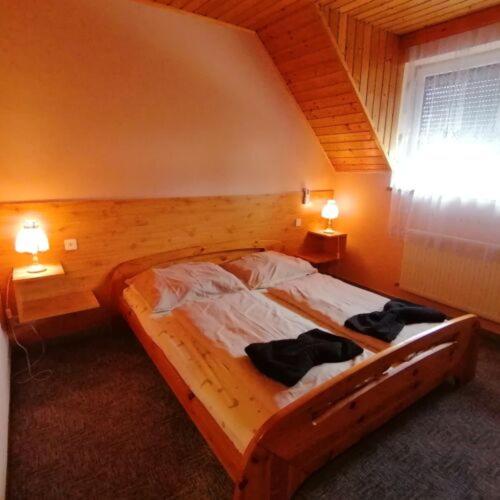 a bedroom with a wooden bed with two towels on it at Malom Fogadó in Balatonboglár