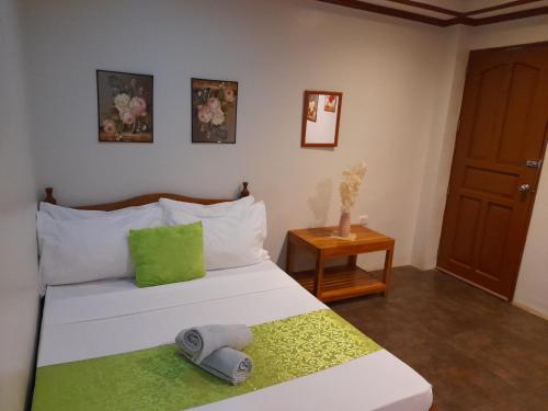 a bedroom with a white bed with a green pillow at MilVir Tourist INN in El Nido
