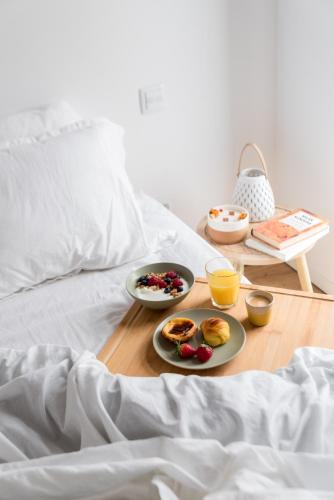 a breakfast tray with breakfast foods on a bed at Lux 56 Praia da Barra Aveiro A 20 metros da Praia in Praia da Barra