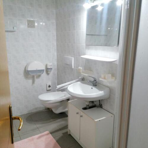 a white bathroom with a toilet and a sink at Malom Fogadó in Balatonboglár