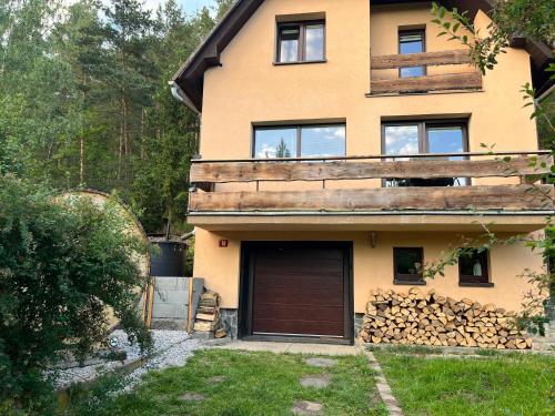 Chyše的住宿－Chata s panoramatickou saunou，一座房子,里面设有车库和一堆木柴