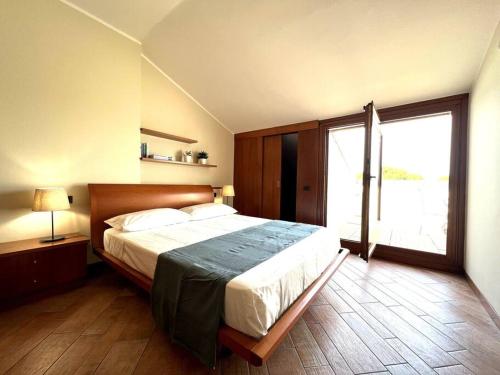 ein Schlafzimmer mit großem Bett und großem Fenster in der Unterkunft Attico in Piazza Matteotti in Desenzano del Garda