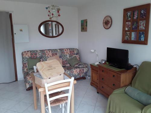 un salon avec un canapé et une table avec une télévision dans l'établissement ker Mamie, à Merville-Franceville-Plage
