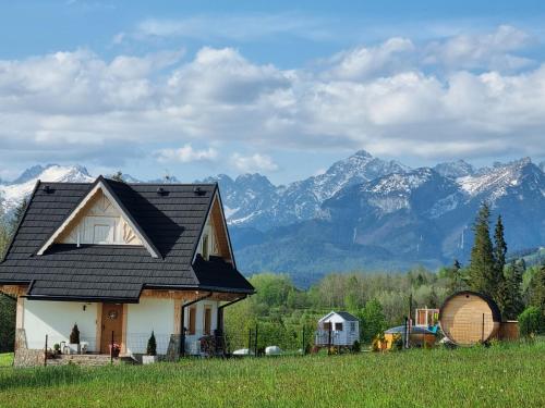 a house with a black roof with mountains in the background at W Sercu Tatr in Rzepiska