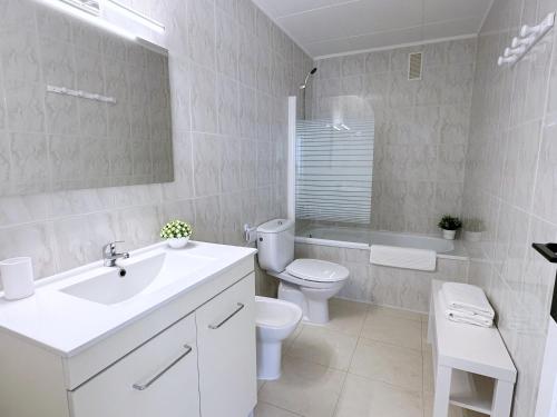 een witte badkamer met een toilet en een wastafel bij AT-Pineda-03 in La Pineda