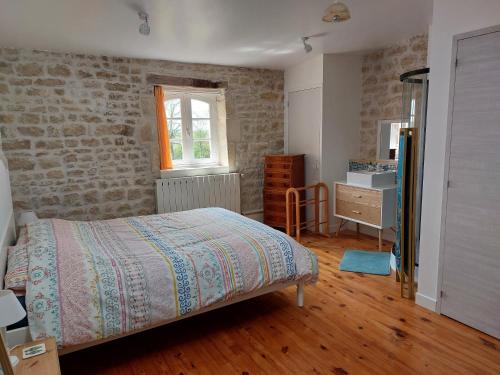 a bedroom with a bed and a brick wall at Maison Rouge in Saint-Jean-dʼAngély