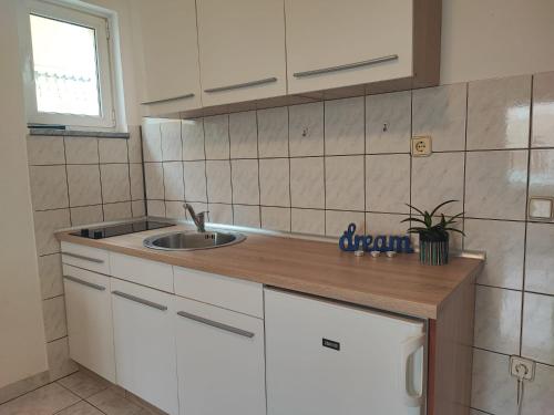 a kitchen with white cabinets and a sink and a window at Apartman Luka in Vodice