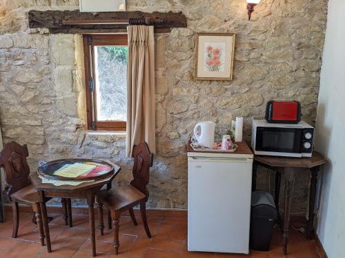 eine Küche mit einem kleinen Tisch und einer Mikrowelle in der Unterkunft chambre d'hôte La Fontaine in Saint-Michel-Lapujade