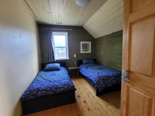 two beds in a small room with a window at 23Maple in Haliburton