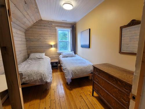a bedroom with two beds and a dresser and a window at 23Maple in Haliburton