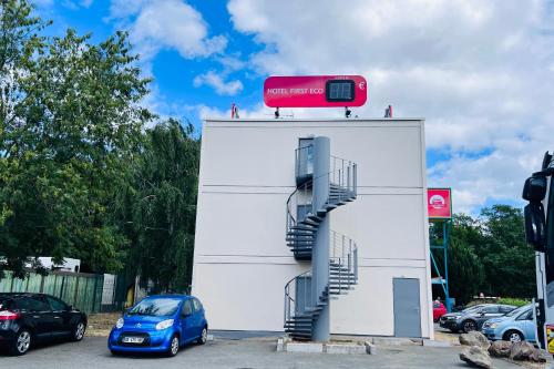 a car parked next to a white building with stairs at Hotel First Eco Savigny Villemoisson Centre Commercial Carrefour in Savigny-sur-Orge