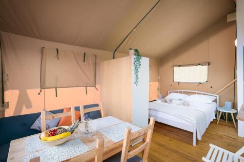 Zimmer mit einem Esstisch und einem Bett in der Unterkunft Prima insula glamping in Brusići