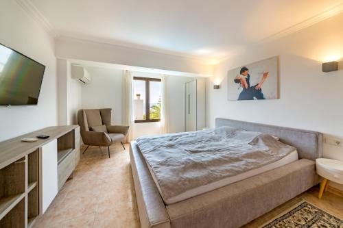 Schlafzimmer mit einem Bett, einem TV und einem Stuhl in der Unterkunft Ferienhaus Casa Kristel in Badia Gran