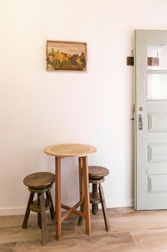 a table and two stools in front of a door at Pátio Serrano in Rio Maior