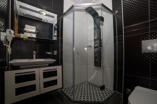 a black and white bathroom with a shower and a sink at Kuzey Park Hotel in Gokceada Town