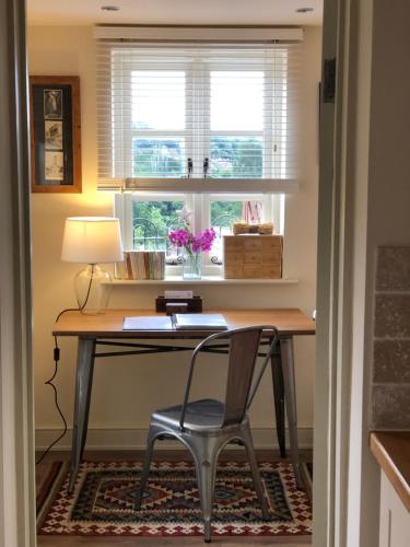 a desk with a chair in front of a window at Shining Star, Cartway River Views in Bridgnorth