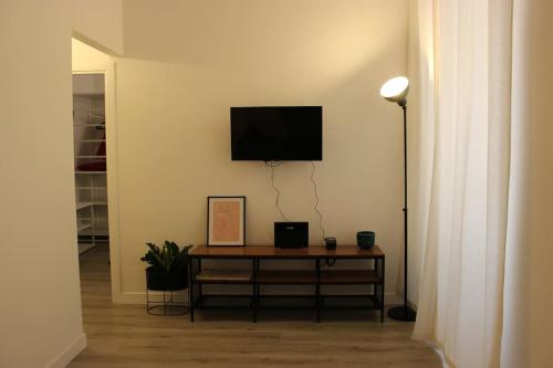 uma sala de estar com uma mesa e uma televisão na parede em Colosseo Living Suites em Roma