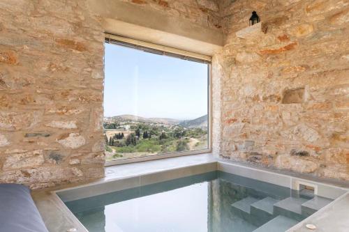 an indoor swimming pool with a window in a stone wall at Villa Gaia - Traditional Stone Villa in Rózia