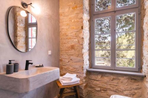kamienna łazienka z umywalką i lustrem w obiekcie Villa Gaia - Traditional Stone Villa w mieście Rózia