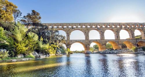 un puente sobre un río con árboles y agua en Maison dans le Gard, en Saint-Gervasy