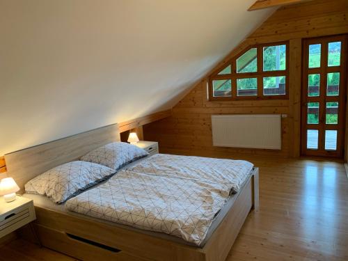 a bedroom with a bed with two night stands and windows at log cabin in Czech-Saxon Switzerland in Šluknov