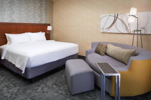 une chambre d'hôtel avec un lit et un canapé dans l'établissement Courtyard Detroit Dearborn, à Dearborn