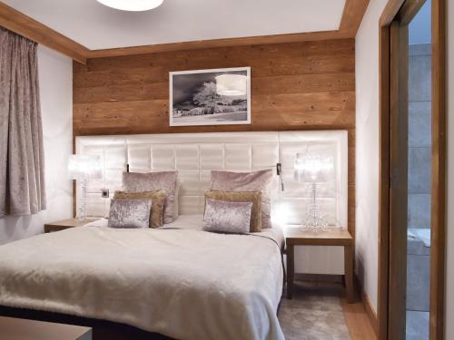 a bedroom with a white bed with a wooden wall at Appartement Courchevel 1550, 2 pièces, 4 personnes - FR-1-562-52 in Courchevel