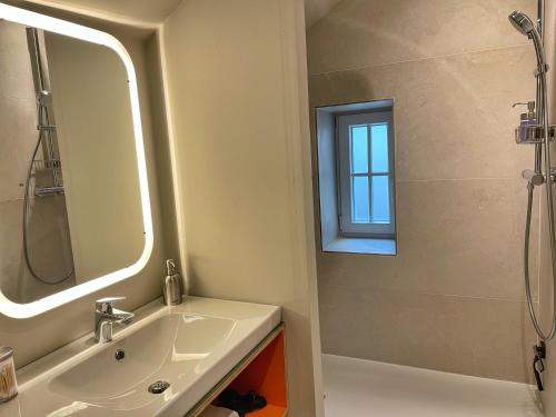 a bathroom with a sink and a shower with a mirror at L'Art de la fugue in Daverdisse