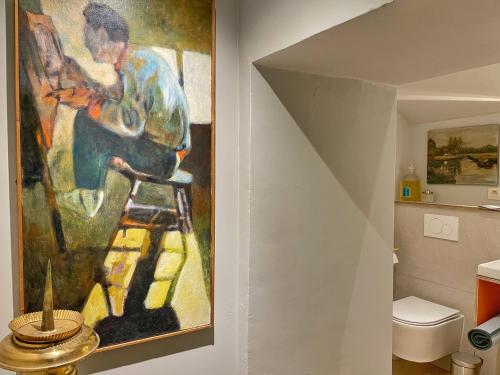 a painting of a man sitting on a stool in a bathroom at L'Art de la fugue in Daverdisse