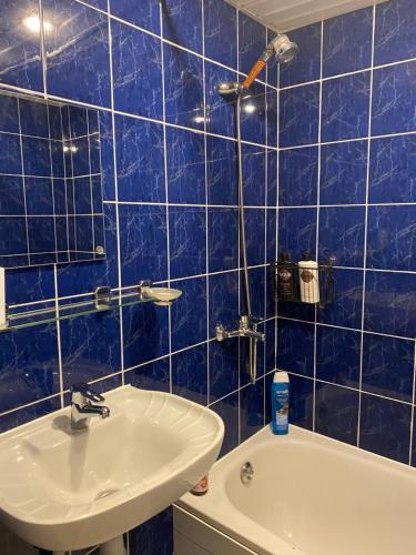 a blue tiled bathroom with a sink and a tub at Oja 134 Apartments in Pärnu