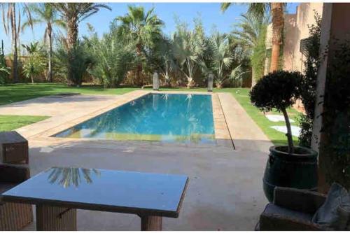 a swimming pool with a table in front of a house at Pavillon avec piscine privée - AL MAADEN Marrakech in Marrakesh