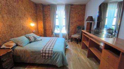 - une chambre avec un lit, une commode et un bureau dans l'établissement El Arca, à Ponferrada