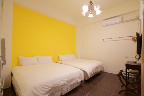 two beds in a room with a yellow wall at Trip Village-Hulk's Homestay in Taitung City