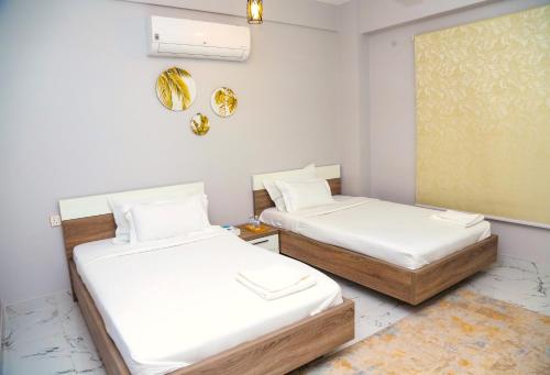 AECO lovely 2 bedroom apartment for family and friends في مسقط: سريرين في غرفة بجدران بيضاء
