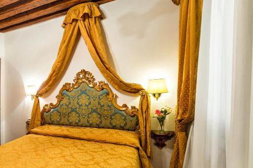 a bedroom with a gold bed with a canopy at Hotel Al Vagon in Venice