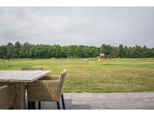 a picnic table with two chairs and a field at Bungalow on Texel with a spacious terrace in De Cocksdorp