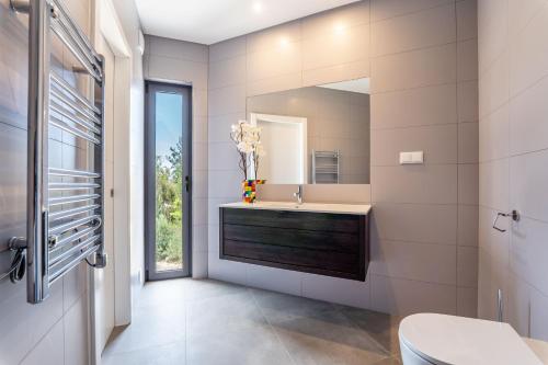 ein Bad mit einem Waschbecken und einem Spiegel in der Unterkunft Villa Vogue by Indigo in Estômbar