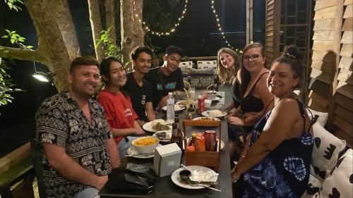 un grupo de personas sentadas alrededor de una mesa con comida en topp stay hostel en Pai