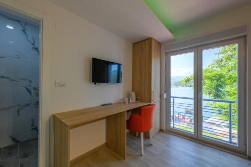 Habitación con escritorio, TV y ventana. en Lakeside Luxury Apartments, en Jablanica
